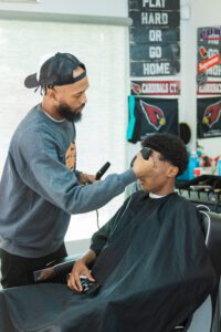 A barber is cutting the hair of another man.