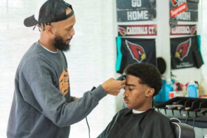 A barber is cutting the hair of another man.