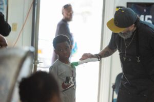 A man is helping a young boy brush his teeth.