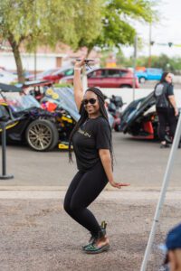 A woman in black shirt holding up a skateboard.