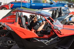 A man driving an orange and black vehicle.