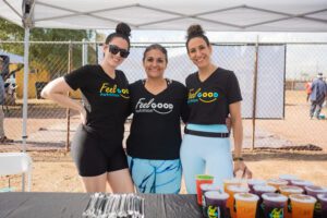 Three women standing next to each other under a tent.