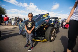 A young boy standing next to a car.