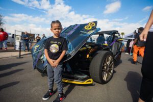 A young boy standing next to an open car.