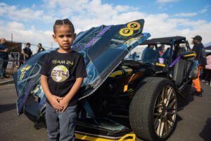 A young boy standing next to an open car.