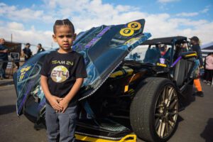 A young boy standing next to an open car.