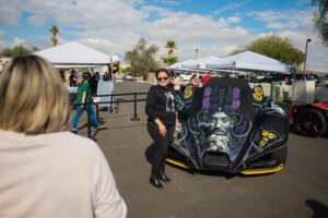 A woman standing next to a car with a skull on it.