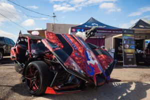 A red and black car parked in front of a tent.