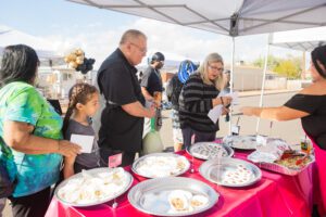 A group of people standing around a table with plates.