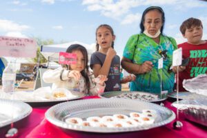 A woman and two girls are eating food.