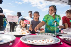 A woman and two children are serving food.