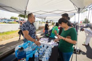 A group of people standing around a table with water.