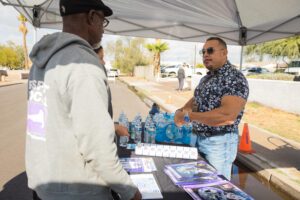 Two men standing under a tent talking to each other.