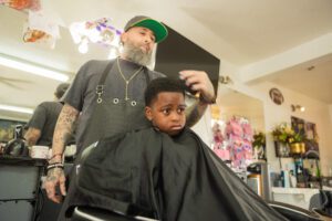 A man is cutting the hair of a young boy.