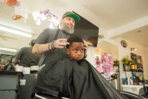 A barber giving a child a haircut in his chair.