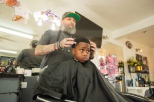 A barber giving a child a haircut in his chair.