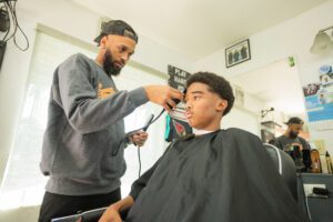 A barber is cutting the hair of a young man.