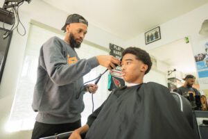 A barber is cutting the hair of a young man.