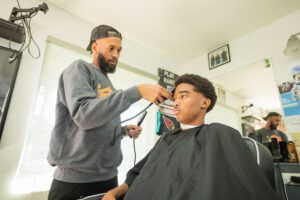 A barber is cutting the hair of a young man.