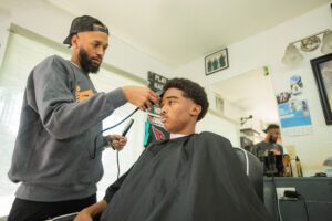 A man getting his hair cut by another man.