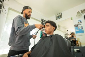 A barber is cutting the hair of a young man.