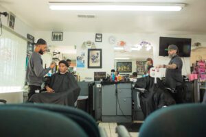 A barber shop with several people sitting in chairs.