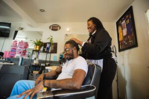 A woman is cutting the hair of a man.