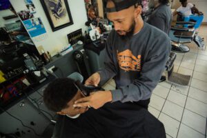 A man cutting another mans hair in a barber shop.