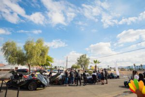 A group of people standing around parked cars.