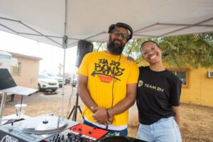 Two people standing next to a dj booth.