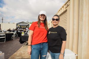 Two women standing next to each other outside.