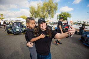 A woman and child taking a selfie in front of some cars.