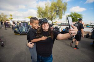 A woman and child taking a selfie in front of some cars.