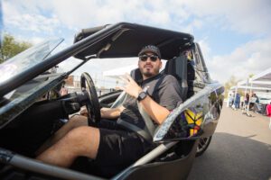 A man sitting in the driver 's seat of an open car.