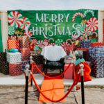 A man sitting in front of a merry christmas sign.