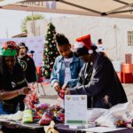 A group of people standing around wrapping gifts.