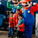 A group of kids posing with mario and luigi.