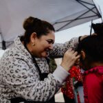 A woman is fixing another child 's hair.