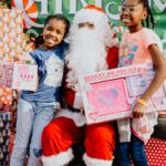 Two girls posing with santa claus in a store.