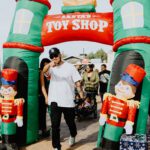 A man standing in front of toy shop inflatable archway.