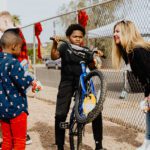 A woman holding onto a bike while two boys stand next to it