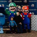 A boy and his family posing with mario characters.