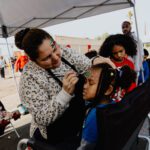 A woman is painting the hair of a child.