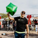 A man holding onto a green kite in the air