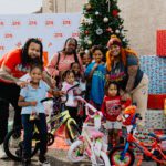 A group of people standing around bicycles and christmas trees.