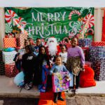 A group of people standing around santa clause.