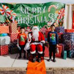 A group of kids standing next to santa clause.