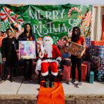 A group of people standing around a santa clause statue.