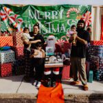 A group of people standing around a table with presents.