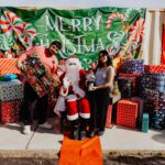 A group of people standing around santa clause.